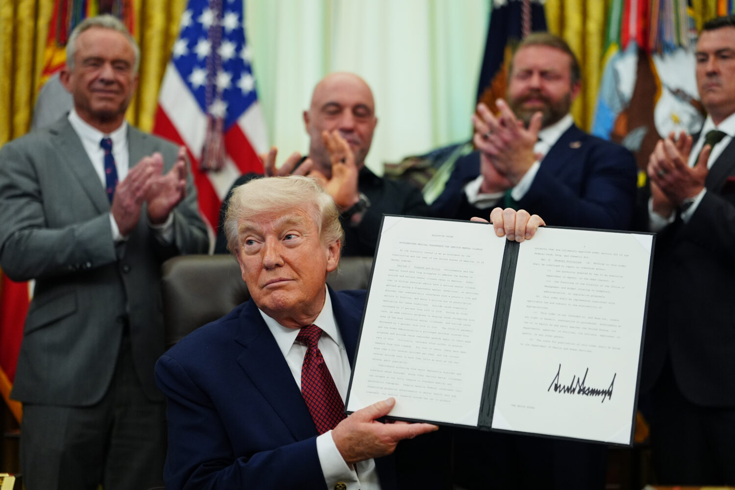 President Donald Trump holds up a signed executive order in the Oval Office of the White House, Sat...