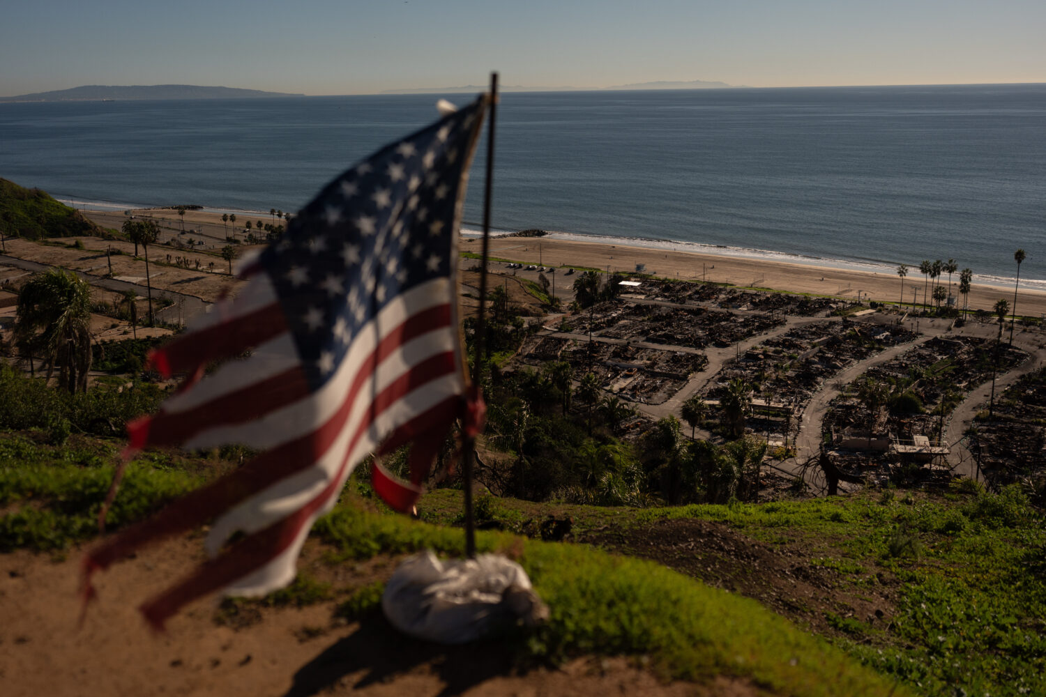 FILE - A tattered U.S. flag flaps in the wind over the remains of a mobile home park that was destr...