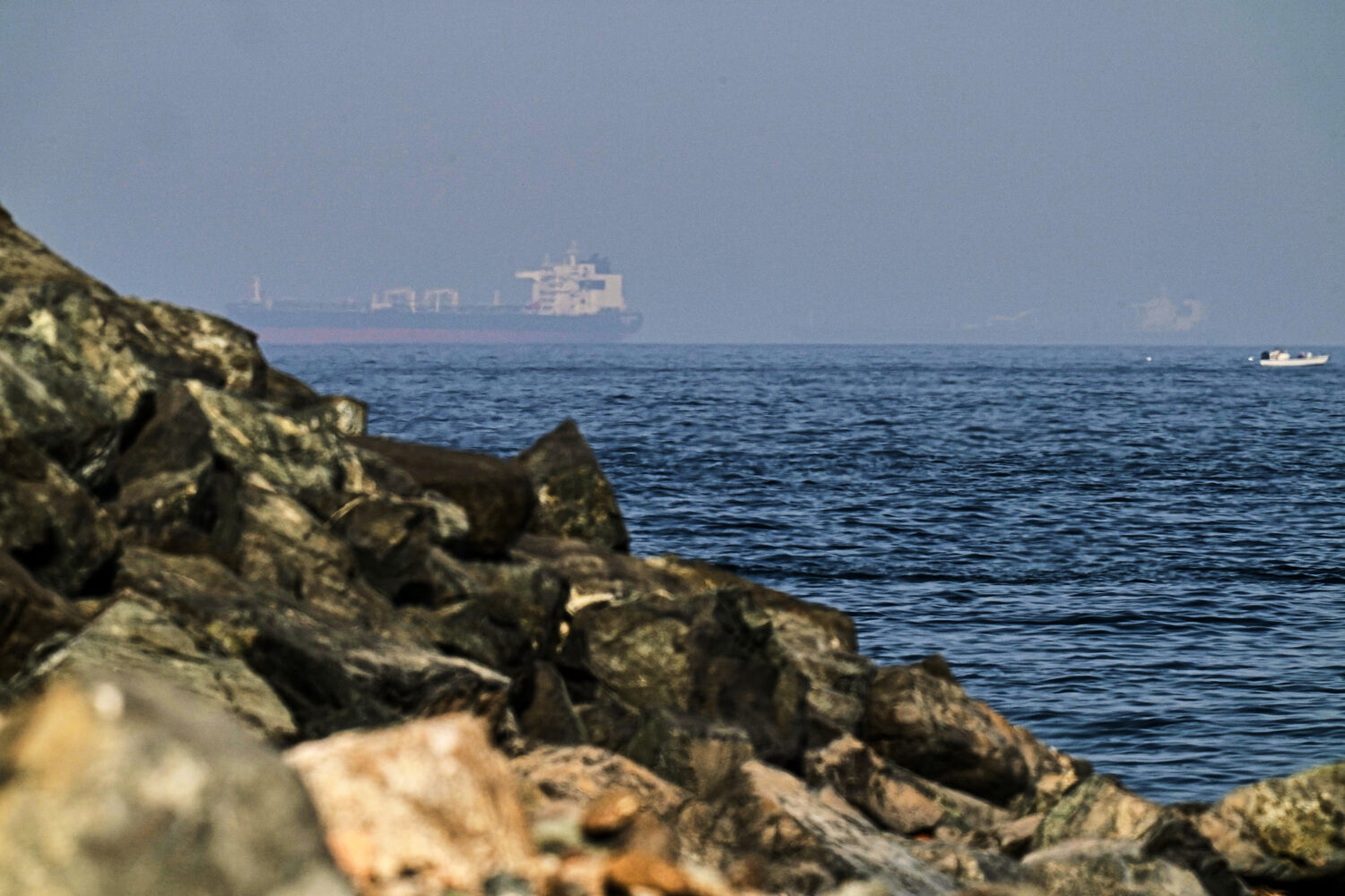 Cargo ships are seen at sea in the Gulf of Oman near the Strait of Hormuz, as viewed from a rocky s...