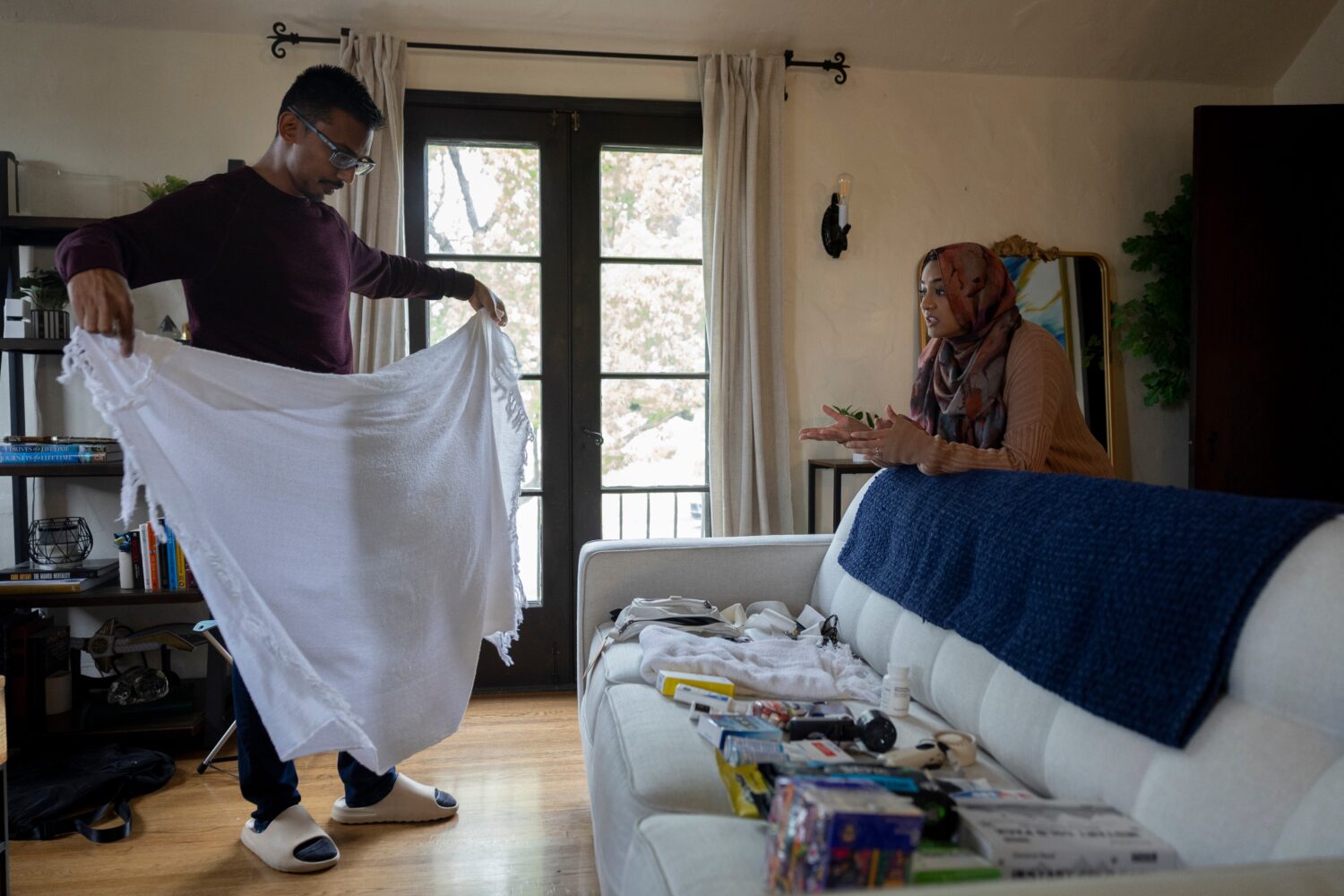 Faisal Rashid, left, practices putting on his ihram robe as he speaks with his wife Samiha Matin as...