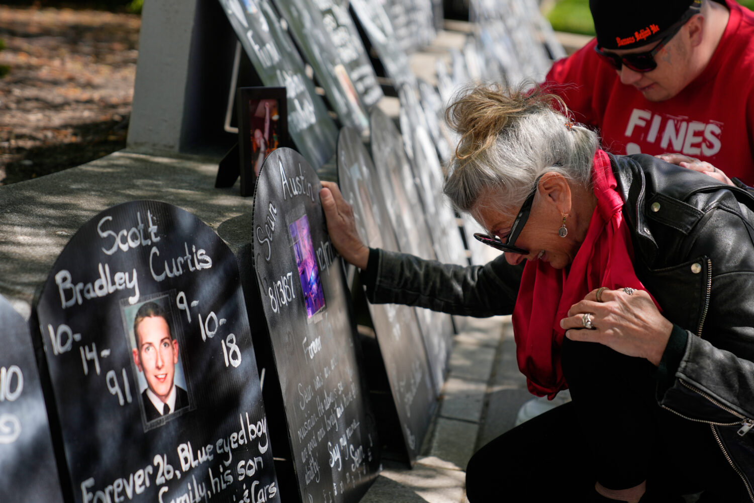 Tanny Austin cries while looking at tombstones with the names of victims of the opioid crisis, incl...