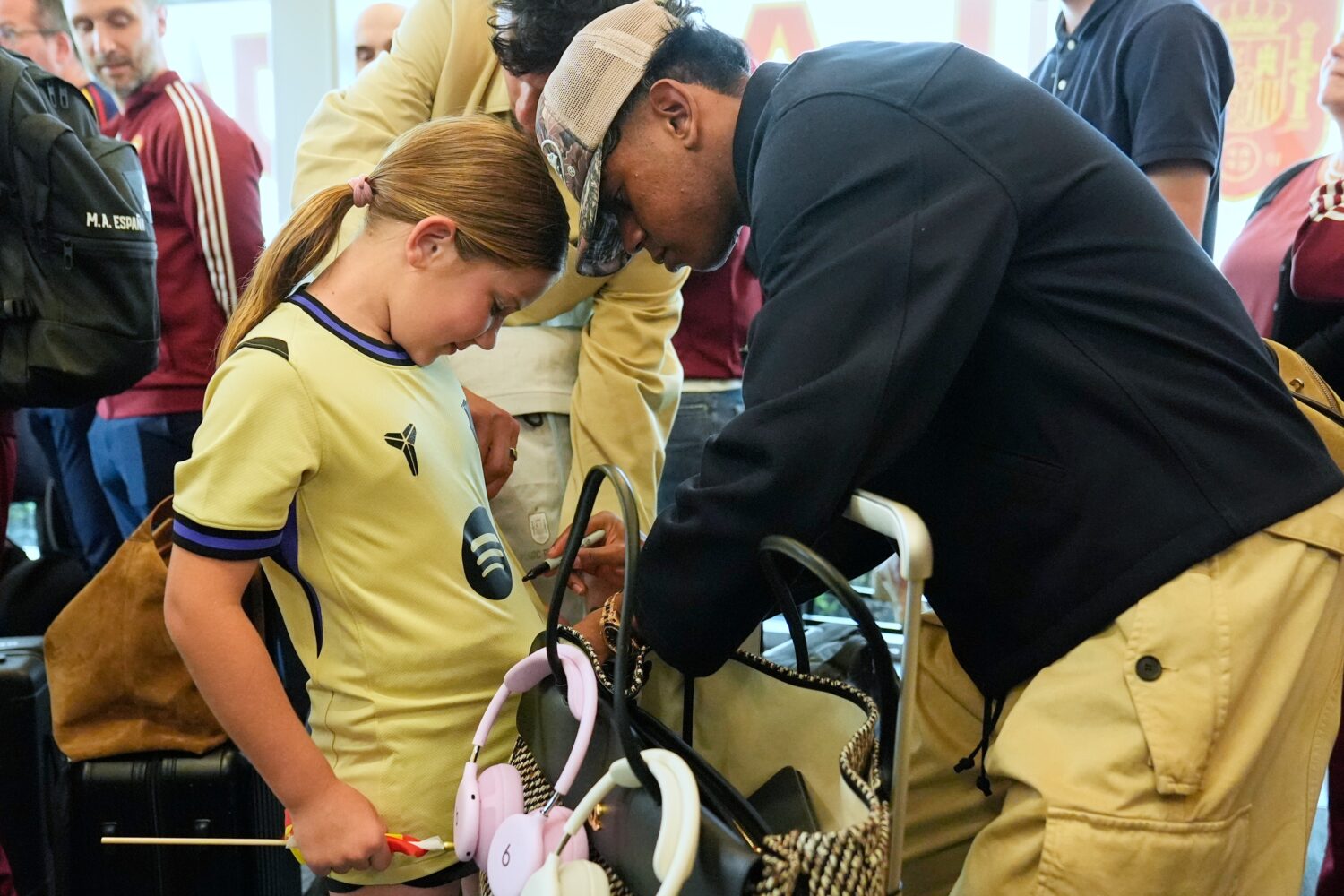Spain midfielder Lamine Yamal, right, signs an autograph for Griffin Wamp, left, after arriving wit...
