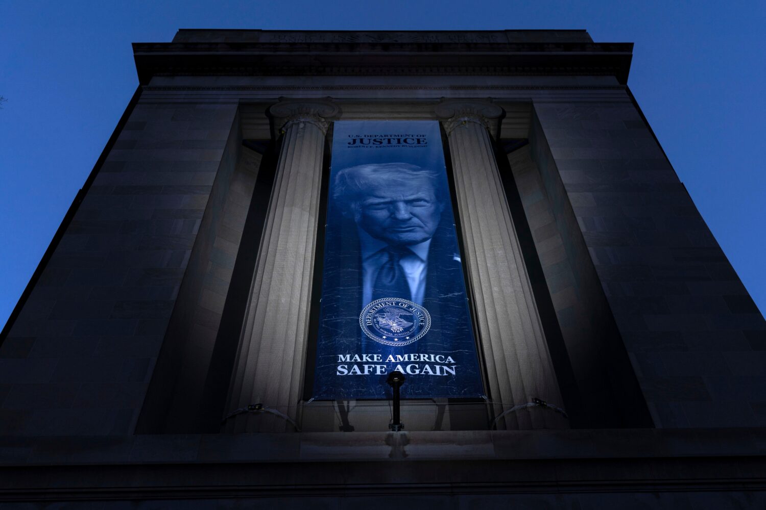 FILE - A banner with a portrait of President Donald Trump is hung from the Department of Justice, M...