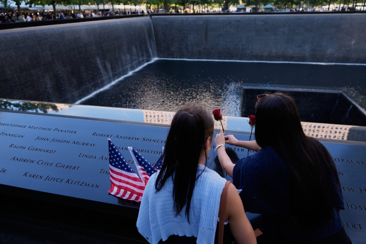 FILE - Ainsley, right, and Sarah Jurccak place a flower in the name of a relative during a ceremony...