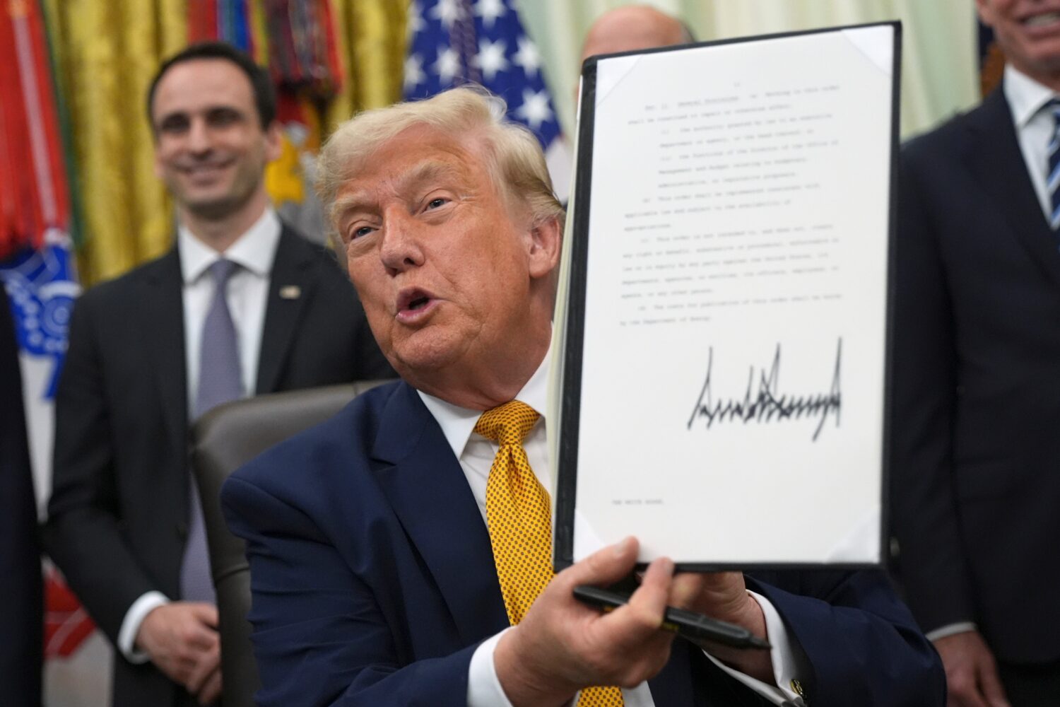 President Donald Trump holds up a signed executive order about quantum computing, in the Oval Offic...