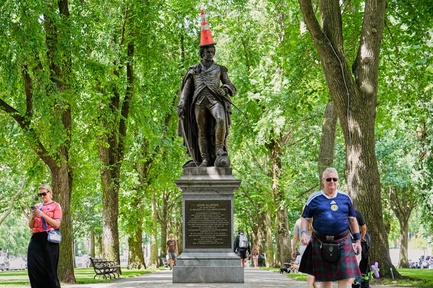 Scottish fans passing a statue of the revolutionary John Glover, humorously decorated with a traffi...